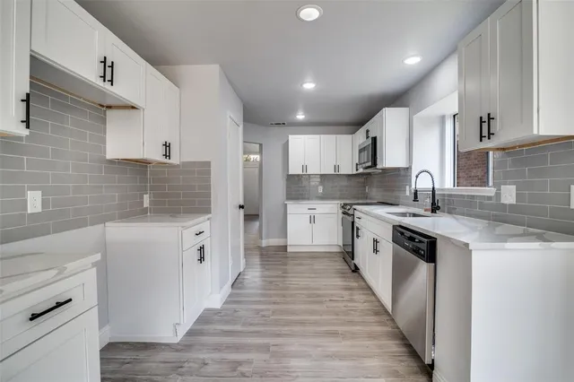 a large kitchen with cabinets a sink a stove a refrigerator and a stove