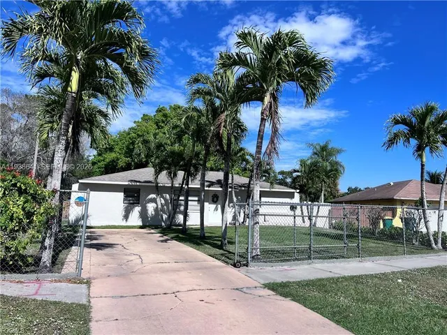 a view of a house with a yard and palm trees