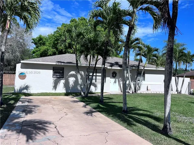 a view of a white house with a big yard and palm trees