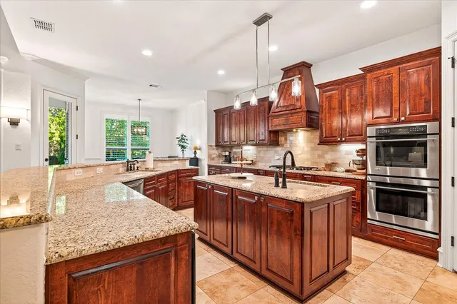 a kitchen with stainless steel appliances granite countertop a kitchen island a stove a sink and a microwave