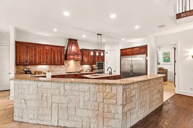 a kitchen with stainless steel appliances granite countertop a sink and a refrigerator