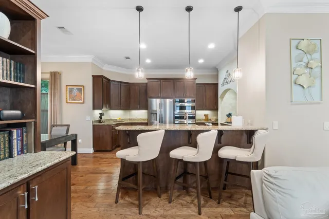 a kitchen with stainless steel appliances granite countertop a sink a stove and a wooden floors