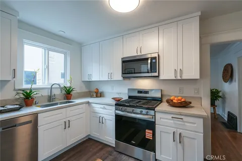 a kitchen with stainless steel appliances white cabinets sink and a window