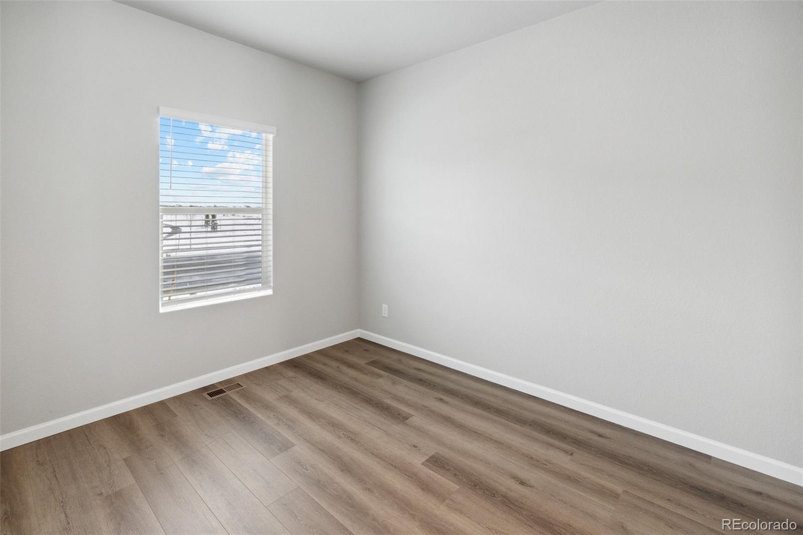 2250 Christina Street Fort Lupton, CO 80621 - Photo 9 of 38 a view of an empty room with wooden floor and a window