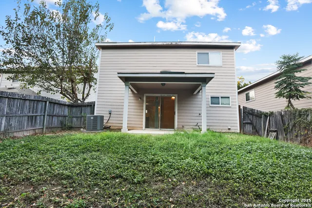 a view of a house with a small yard and a large tree