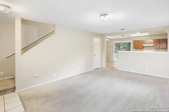 a view of an empty room with kitchen and a window