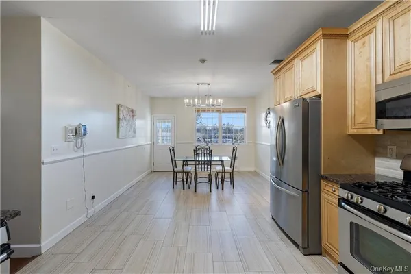 a kitchen with stainless steel appliances a dining table chairs stove refrigerator and cabinets