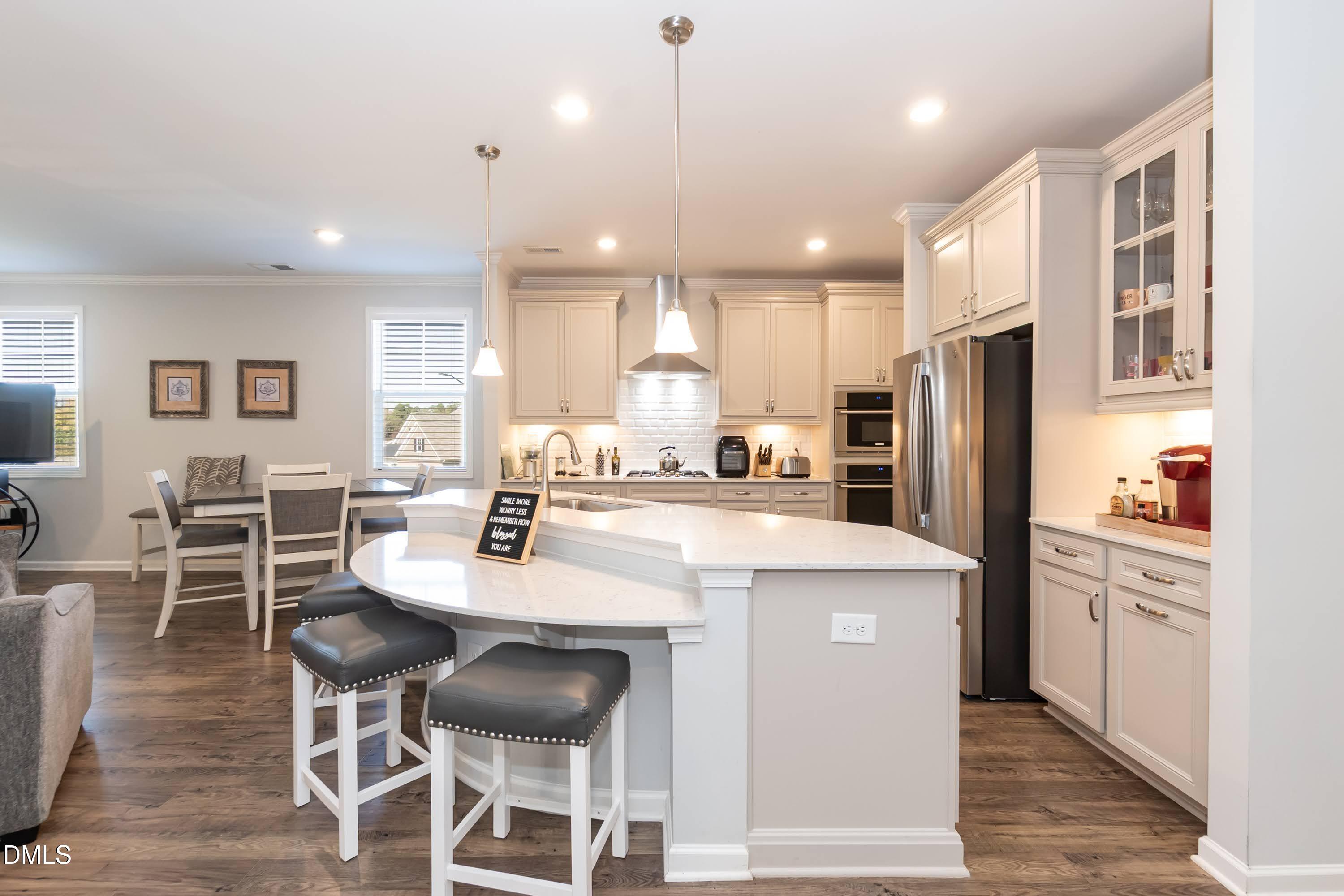1009 Crescent Moon Court Durham, NC 27712 - Photo 26 of 57 a kitchen with stainless steel appliances kitchen island granite countertop a dining table chairs refrigerator and microwave