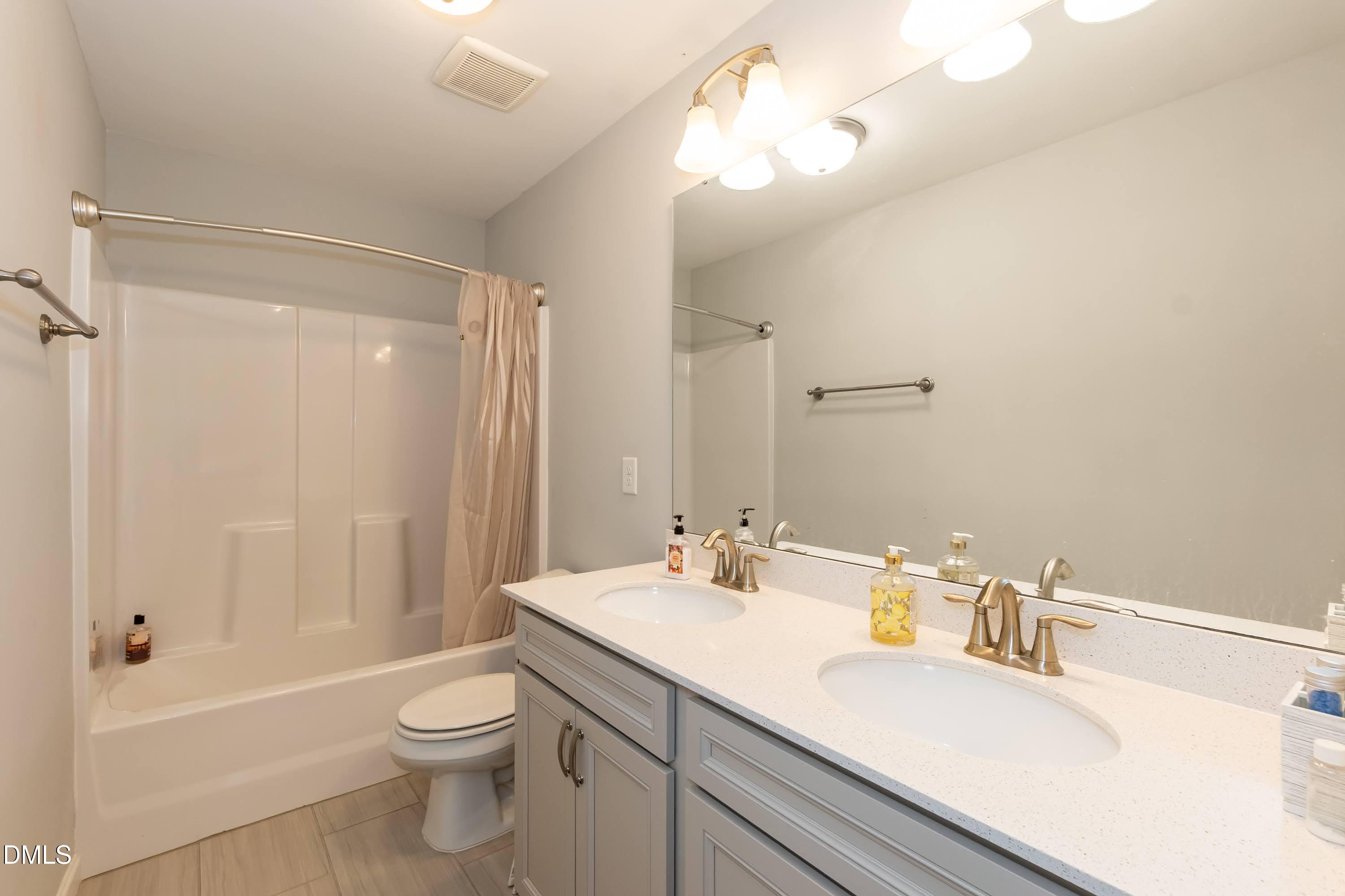 1009 Crescent Moon Court Durham, NC 27712 - Photo 49 of 57 a bathroom with a sink a toilet a mirror and shower