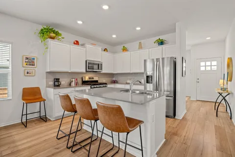 a kitchen with stainless steel appliances granite countertop a refrigerator and a stove top oven with wooden floor