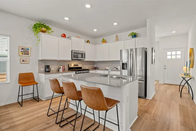 a kitchen with stainless steel appliances granite countertop a refrigerator and a stove top oven with wooden floor