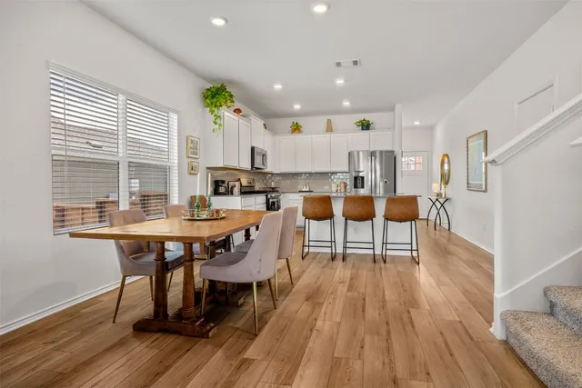 a dining room with stainless steel appliances a table and chairs