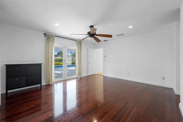 a view of empty room with wooden floor and fan