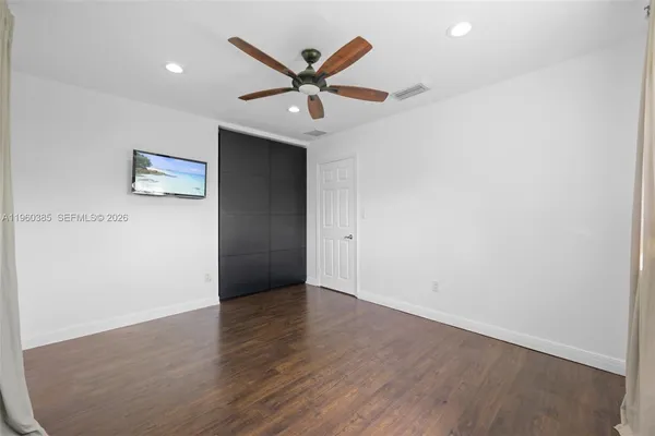 an empty room with ceiling fan and wooden floor