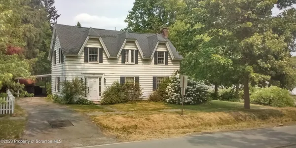 a white house that has a tree in front of it