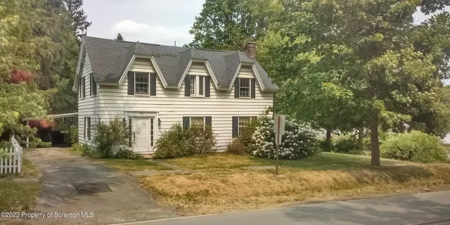 a white house that has a tree in front of it
