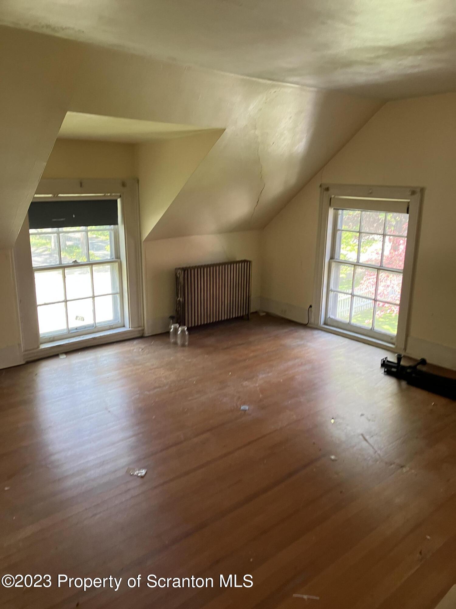 321 Maple Street Montrose, PA 18801 - Photo 16 of 28 an empty room with wooden floor and windows with curtains