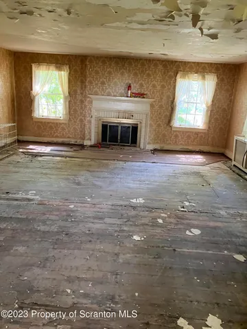 an empty room with a fireplace and windows