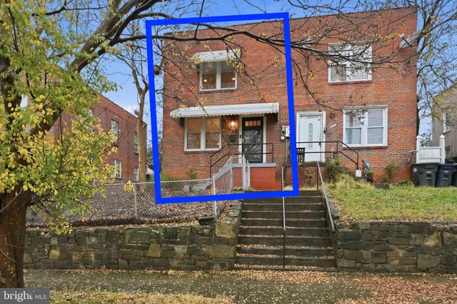 a view of a brick building with a small yard and a large tree