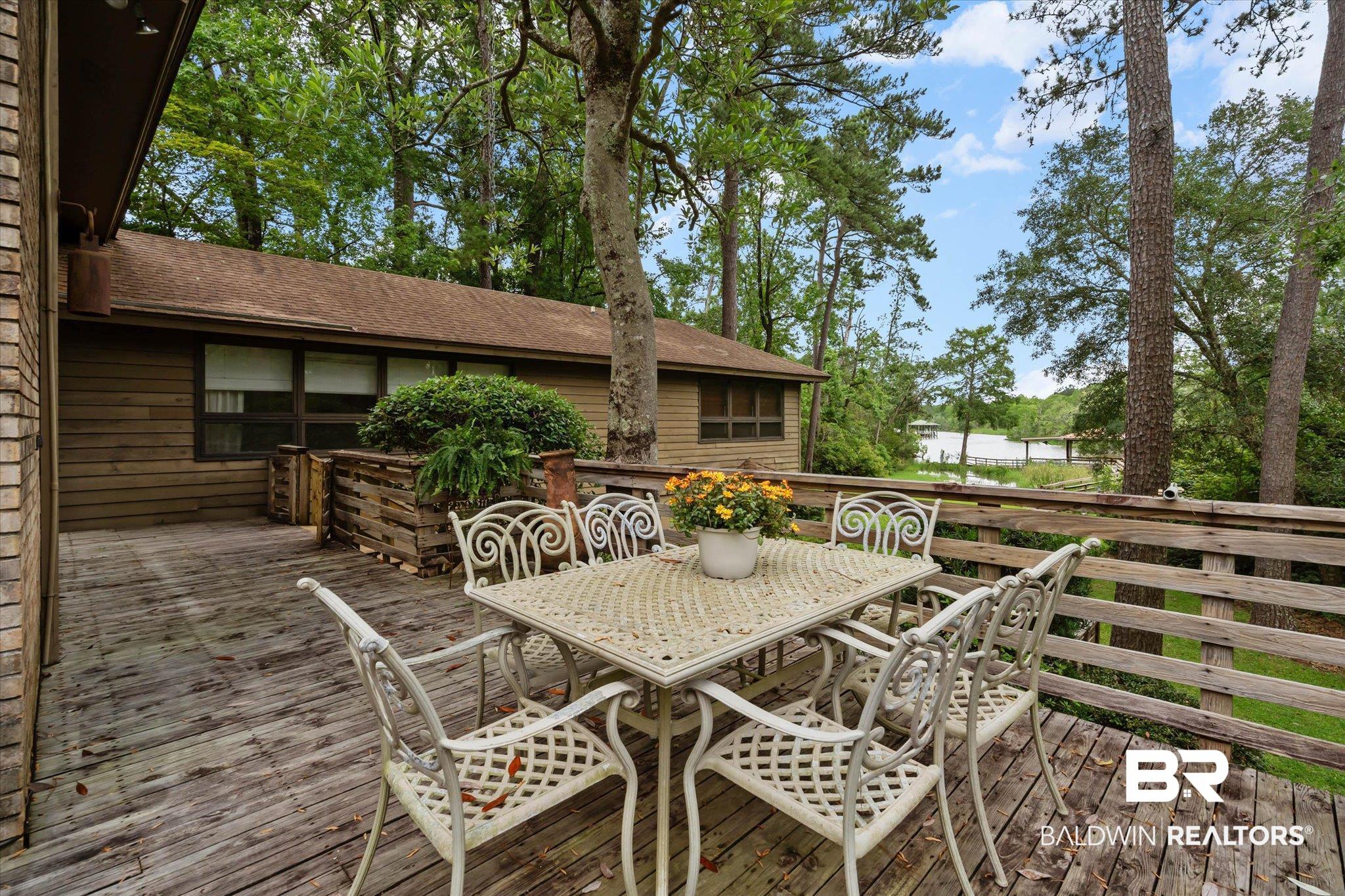3500 Venetia Road Mobile, AL 36605 - Photo 27 of 56 Expansive wood deck with a natural wood railing, surrounded by mature trees, offering a water backdrop