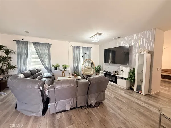 a living room with furniture a flat screen tv and a refrigerator