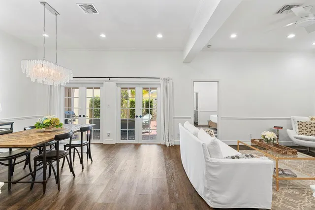 a view of a dining room and livingroom with furniture wooden floor a chandelier