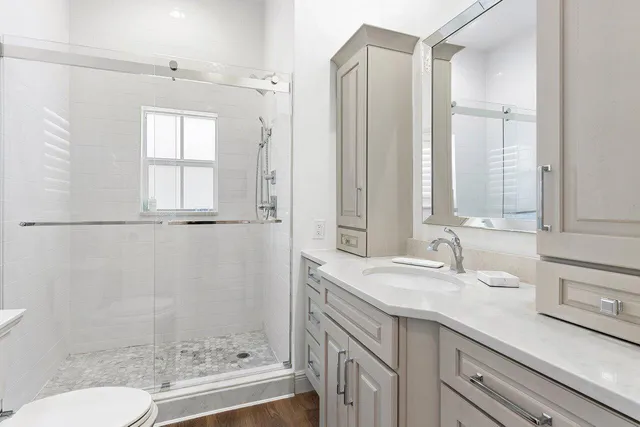 a bathroom with a granite countertop sink a toilet and shower