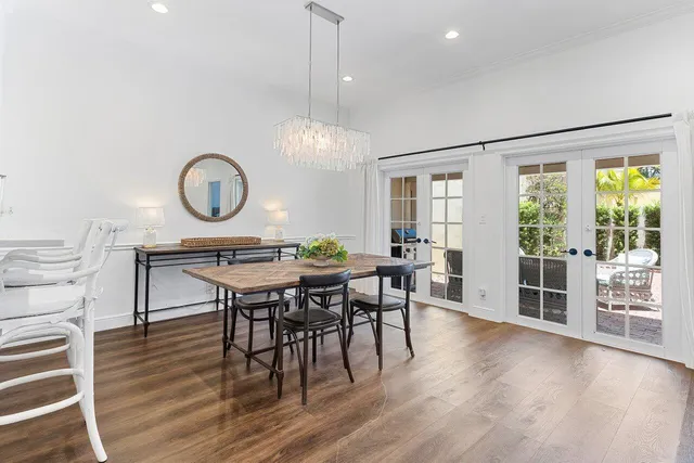 a dining room with wooden floor a chandelier a wooden table and chairs