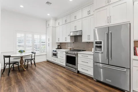 a kitchen with white cabinets stainless steel appliances and wooden floor