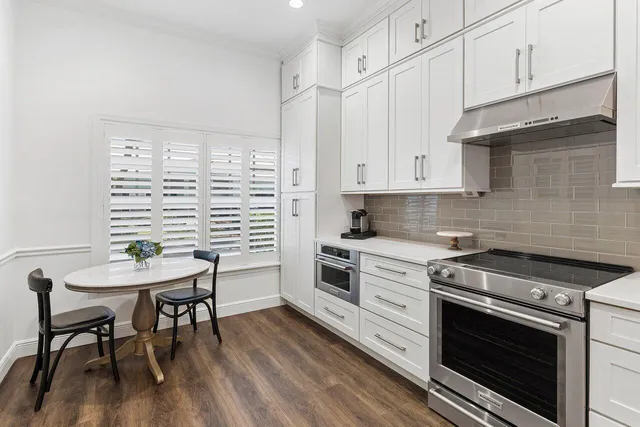 a kitchen with stainless steel appliances white cabinets and wooden floor