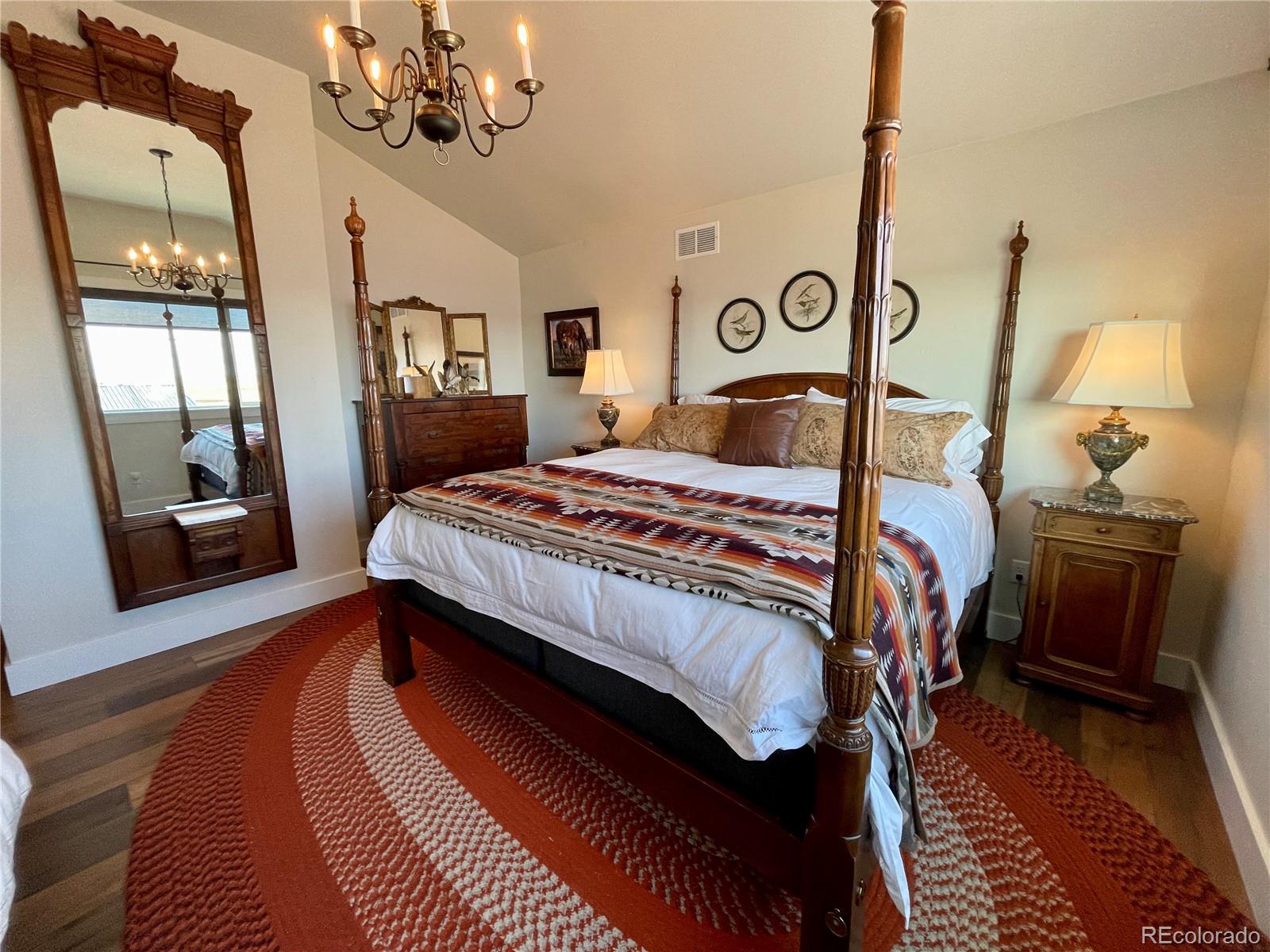 26794 Maul Road Elbert, CO 80106 - Photo 17 of 44 a bedroom with a large bed and a chandelier