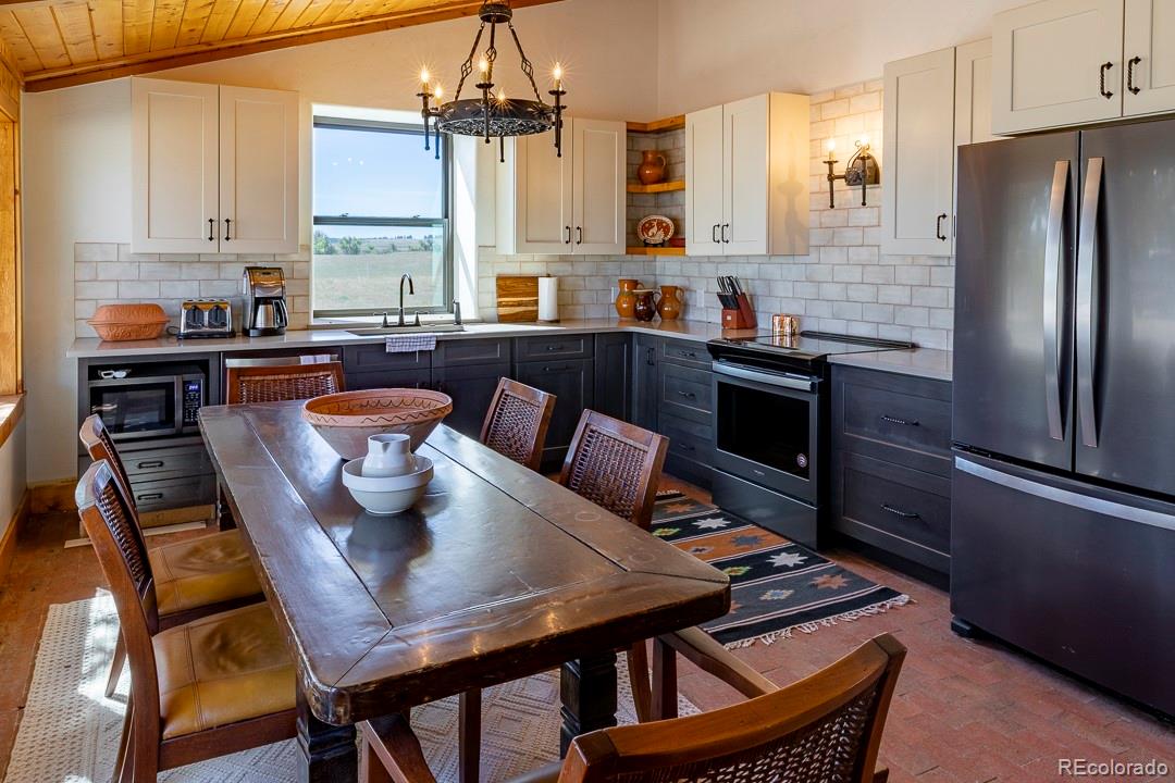 26794 Maul Road Elbert, CO 80106 - Photo 21 of 44 a kitchen with stainless steel appliances granite countertop a stove a refrigerator a dining table and chairs