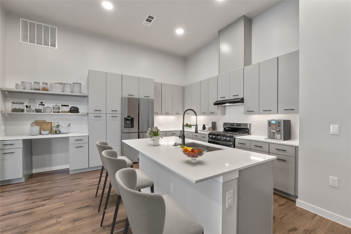 4510 Terry-O Lane, Unit 141 Austin, TX 78745 - Photo 2 of 29 Kitchen featuring visible vents, a high ceiling, appliances with stainless steel finishes, a sink, and under cabinet range hood