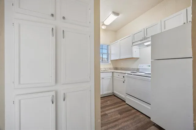 a kitchen with white cabinets and refrigerator