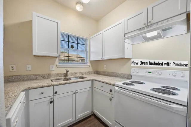 a kitchen with granite countertop a sink a stove and cabinets
