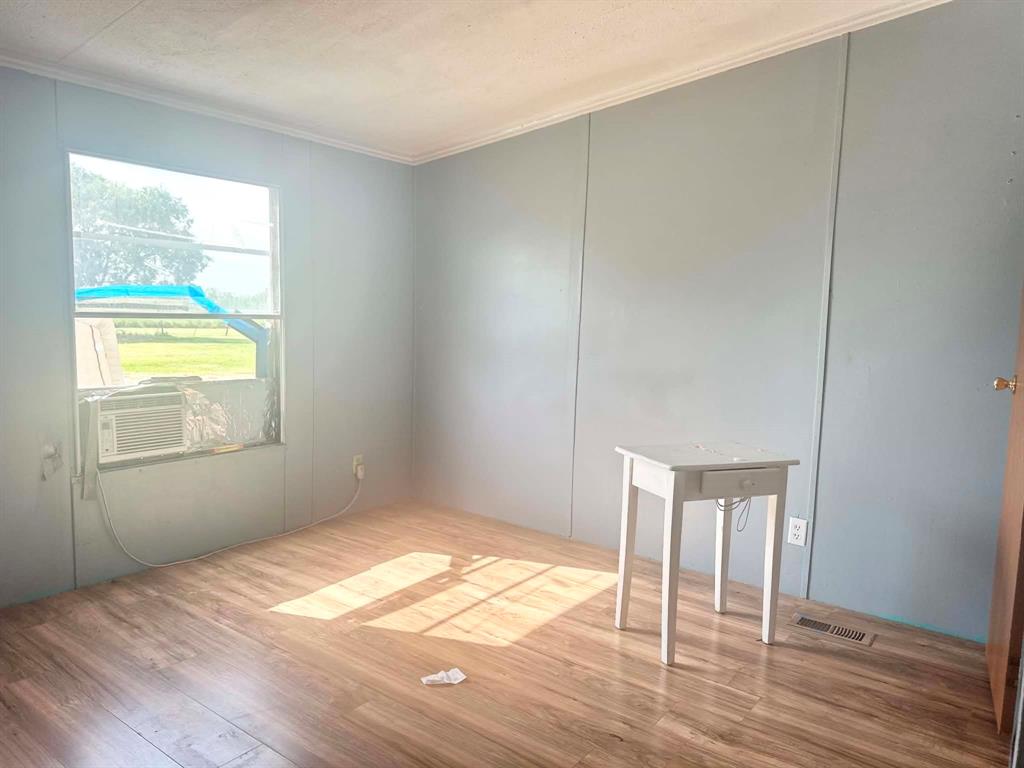 1275 John Wayne Road Kaufman, TX 75142 - Photo 11 of 11 Room featuring wood-finish flooring, light blue panel walls, and white trim