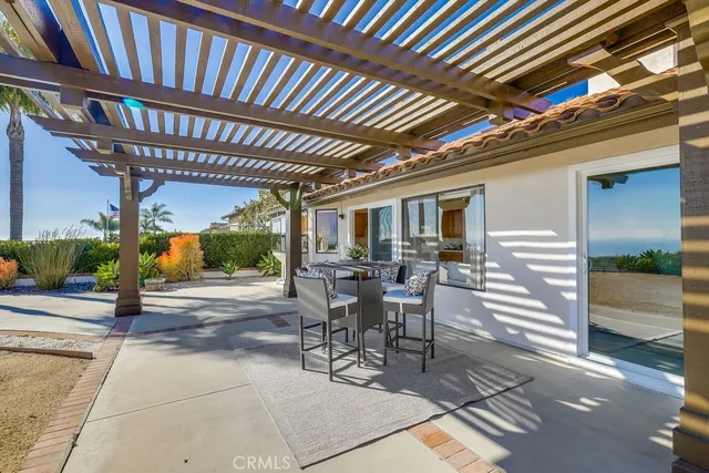 a view of a patio with table and chairs under an umbrella with a small yard