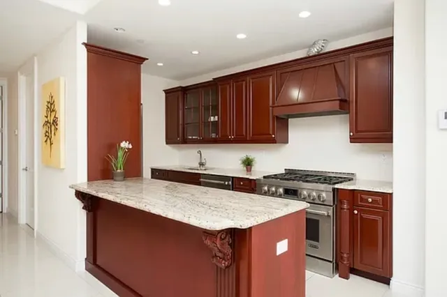a kitchen with stainless steel appliances kitchen island granite countertop a dining table chairs and a refrigerator