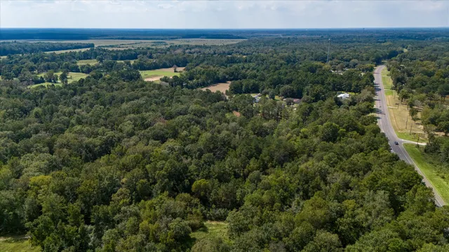an aerial view of residential house with outdoor space and trees all around