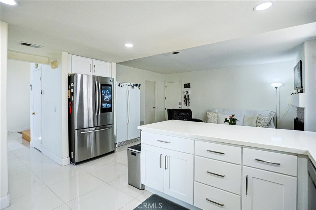 13079 Winterpark Way Riverside, CA 92503 - Photo 14 of 33 a kitchen with white cabinets and refrigerator
