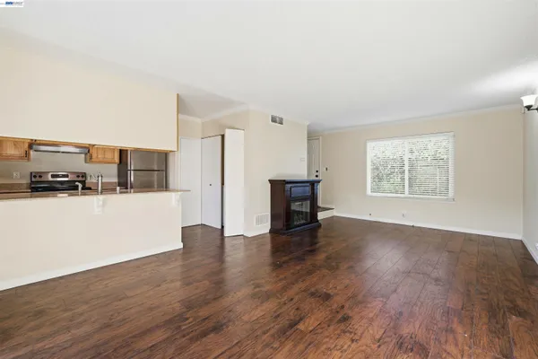 a view of an empty room with wooden floor and a window