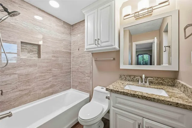 a bathroom with a granite countertop toilet a sink and bathtub