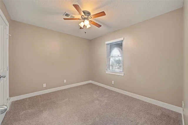 an empty room with a window and a fan