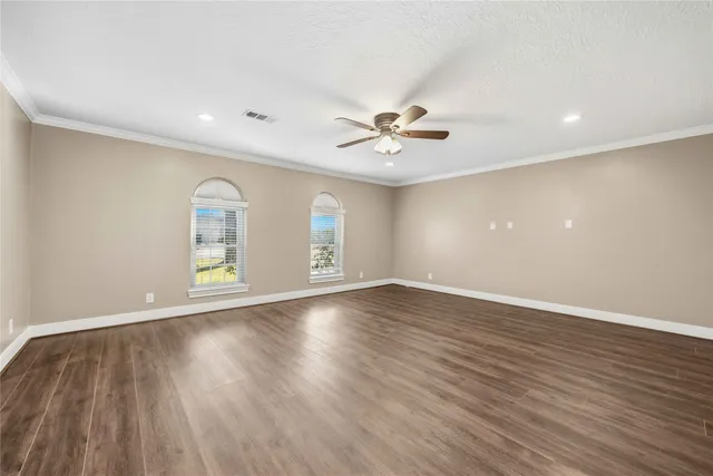 a view of an empty room with a window and wooden floor