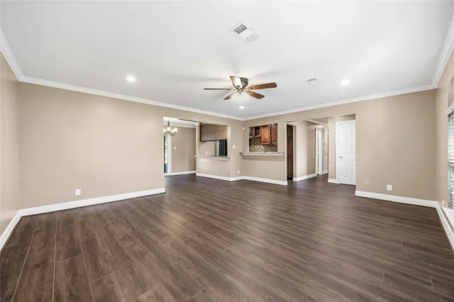 a view of an empty room with a window and wooden floor