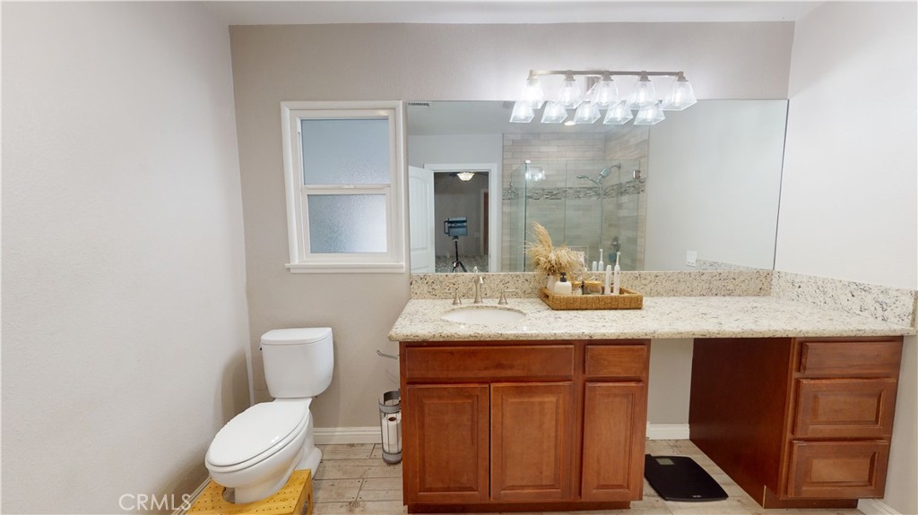 10039 Primrose Drive Riverside, CA 92503 - Photo 18 of 56 a bathroom with a granite countertop sink a toilet and a mirror