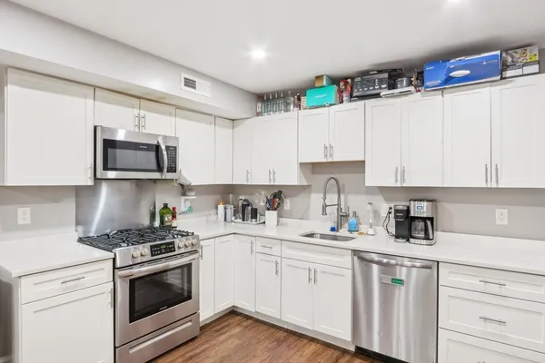 a kitchen with granite countertop white cabinets white stainless steel appliances and sink