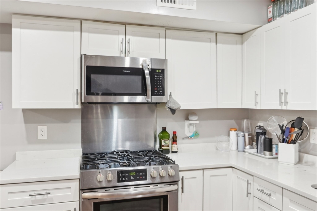 271 West Fifth Street Boston, MA 02127 - Photo 4 of 30 a kitchen with stainless steel appliances a white stove top oven and cabinets