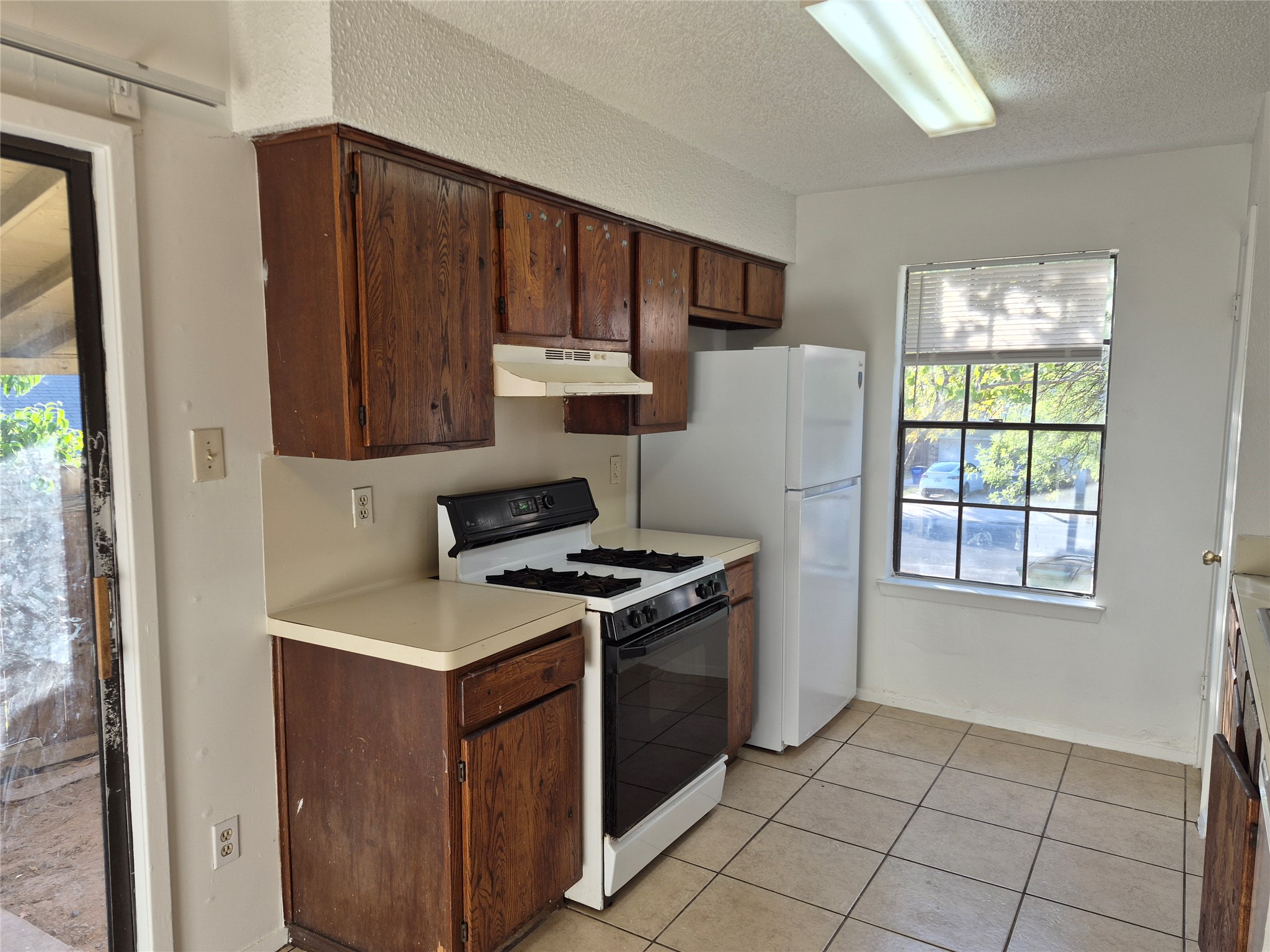 Functional layout highlights this cooking area featuring durable tile flooring and rich wood cabinetry.
