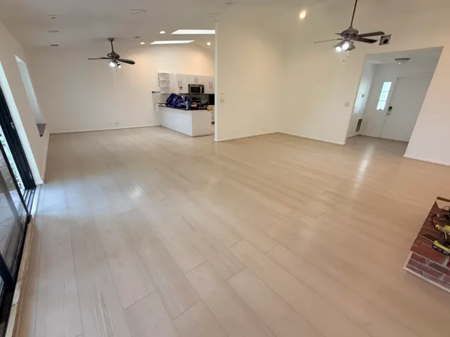 an empty room with wooden floor and a ceiling fan